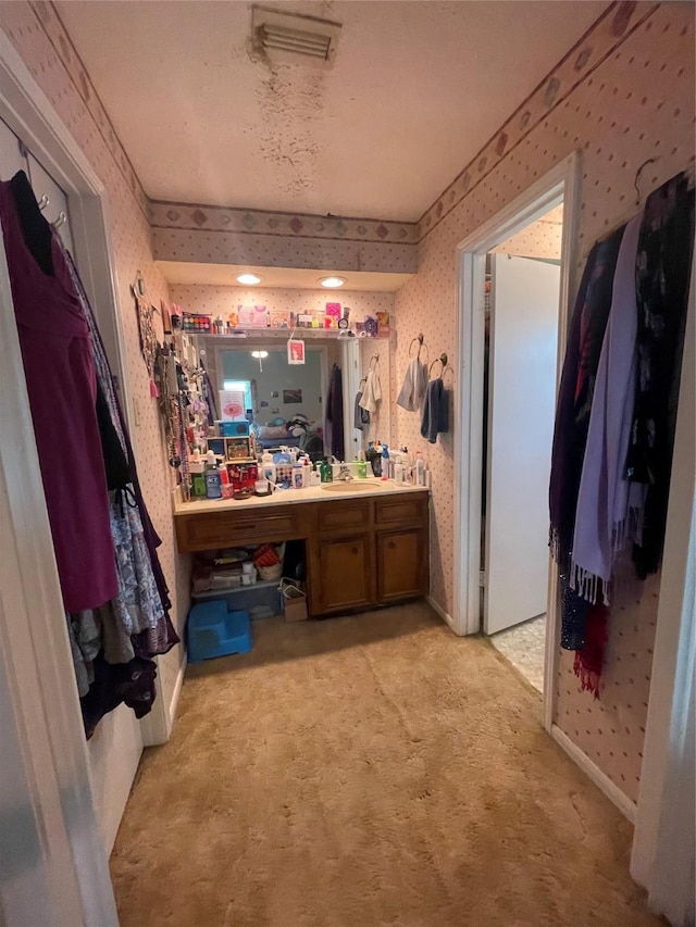 bathroom featuring vanity, visible vents, a workshop area, and wallpapered walls