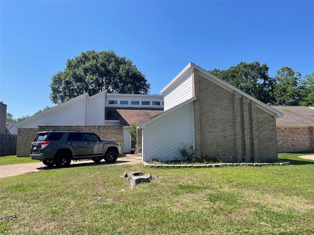 view of side of property featuring brick siding, a yard, and driveway