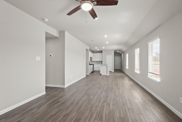 unfurnished living room featuring lofted ceiling, a ceiling fan, baseboards, and dark wood finished floors