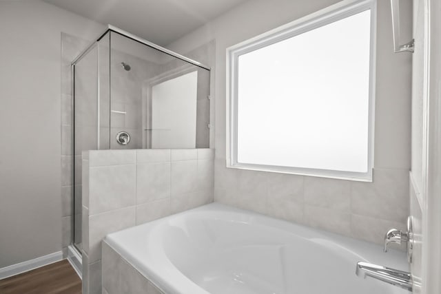 bathroom featuring a garden tub, wood finished floors, and a shower stall