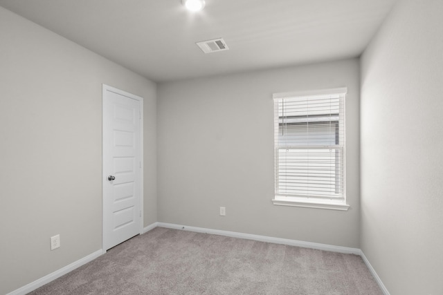 spare room featuring visible vents, baseboards, and light carpet