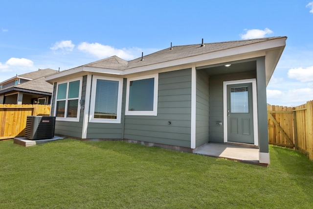 rear view of house with a fenced backyard, central AC unit, and a yard