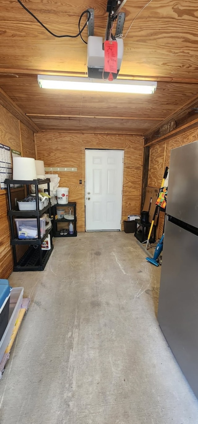101 Tony Ln, Huntsville, TX 77320 - garage featuring wood walls, a garage door opener, wood ceiling, and freestanding refrigerator