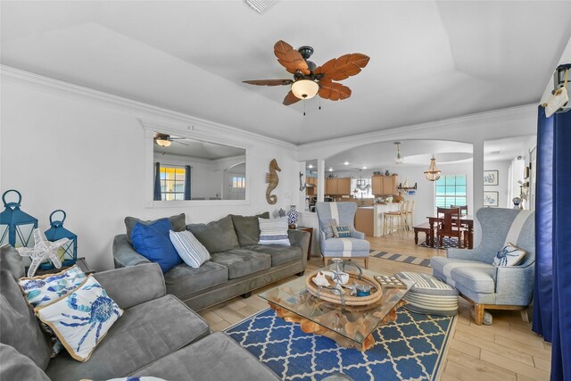 1014 Blue Water Hwy, Surfside Beach, TX 77541 - living room featuring arched walkways, ornamental molding, a ceiling fan, a tray ceiling, and light wood finished floors