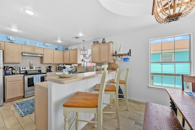 1014 Blue Water Hwy, Surfside Beach, TX 77541 - kitchen with light brown cabinetry, appliances with stainless steel finishes, under cabinet range hood, light countertops, and backsplash