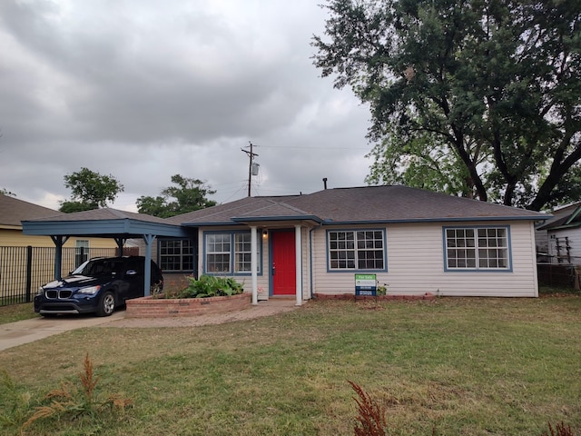 view of front of house with fence, roof with shingles, a front yard, and a carport