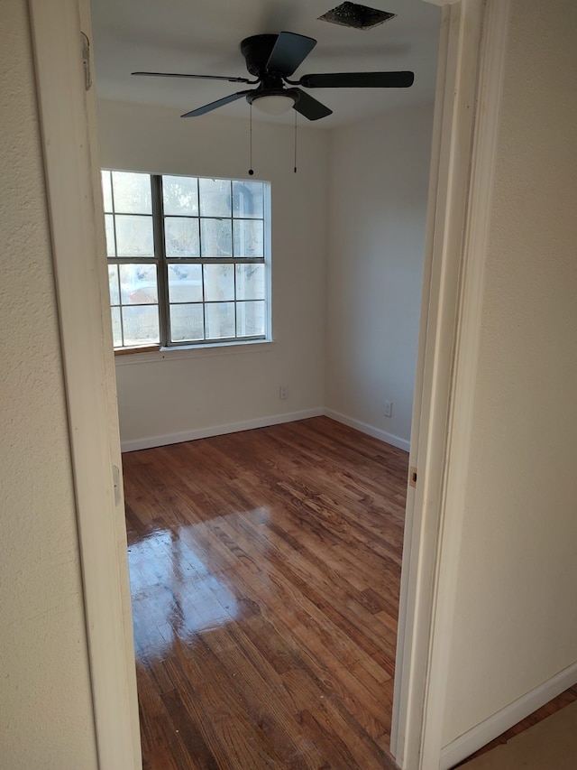unfurnished room featuring visible vents, ceiling fan, wood finished floors, and baseboards