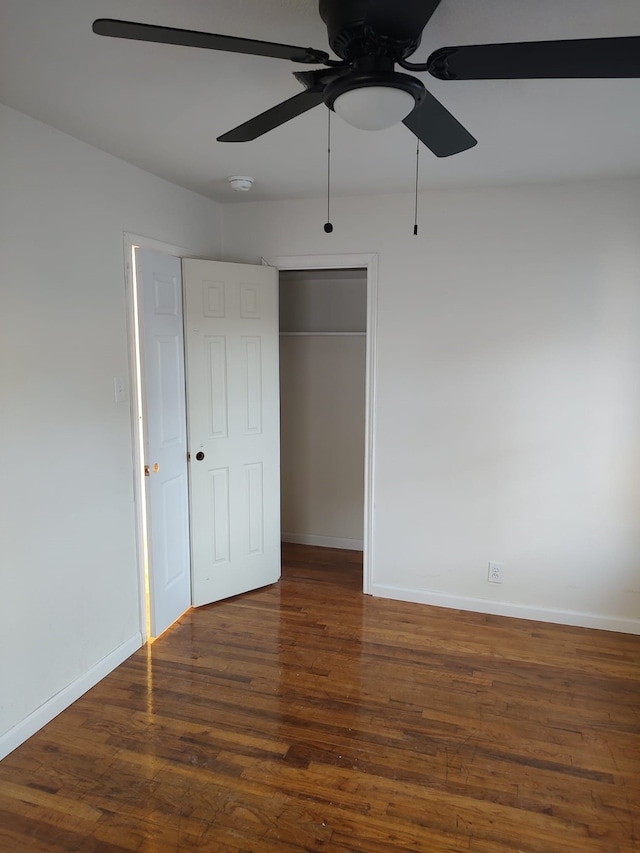 unfurnished bedroom featuring wood finished floors, baseboards, a closet, and a ceiling fan