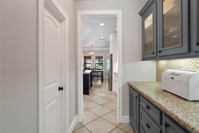 1858 Stoney Brook Ct, Conroe, TX 77304 - bar area with freestanding refrigerator, light tile patterned flooring, decorative backsplash, a chandelier, and baseboards