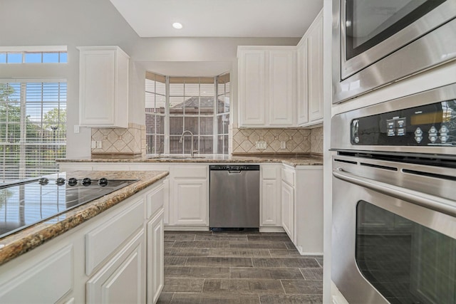 kitchen featuring white cabinets, tasteful backsplash, a sink, and appliances with stainless steel finishes