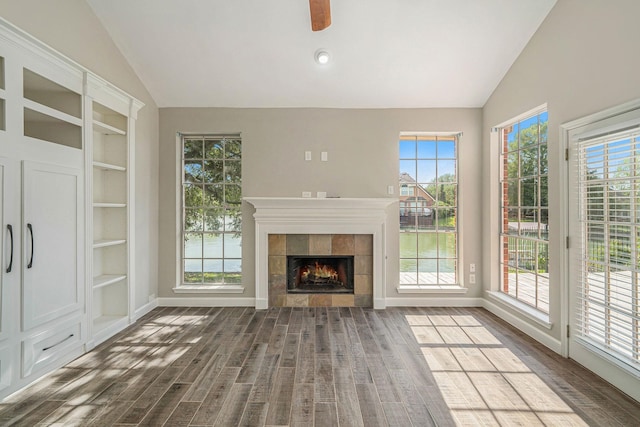 unfurnished living room featuring dark wood-style floors, a tile fireplace, and lofted ceiling