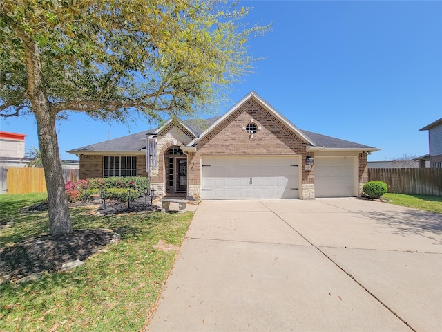 ranch-style house featuring stone siding, fence, brick siding, an attached garage, and driveway