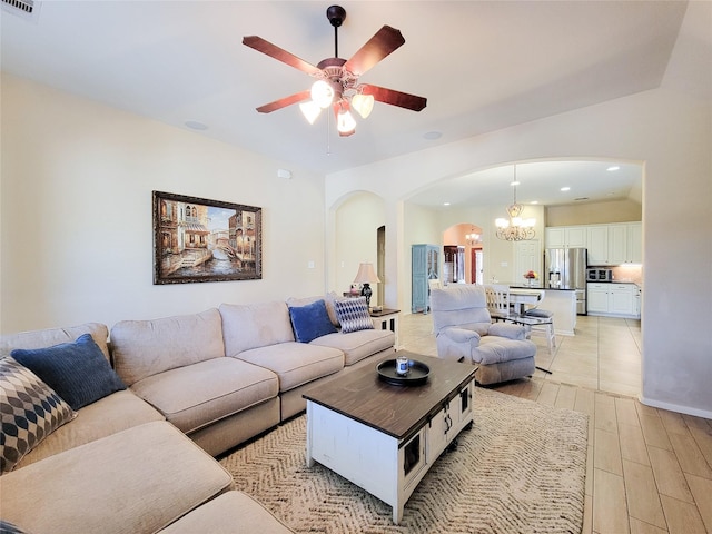 living room featuring arched walkways, ceiling fan with notable chandelier, visible vents, and light wood-style floors