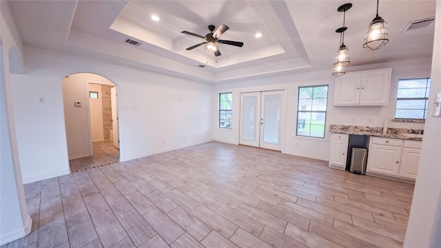 kitchen with arched walkways, visible vents, a tray ceiling, and ceiling fan