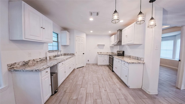 kitchen featuring a sink, wall chimney range hood, stainless steel electric stove, white cabinetry, and wood finish floors