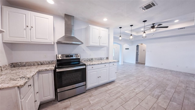 kitchen featuring arched walkways, stainless steel electric range oven, wall chimney range hood, a ceiling fan, and visible vents
