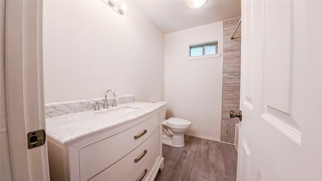 bathroom with toilet, wood finished floors, and vanity