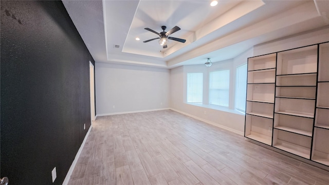 interior space featuring ceiling fan, a raised ceiling, wood finished floors, and baseboards