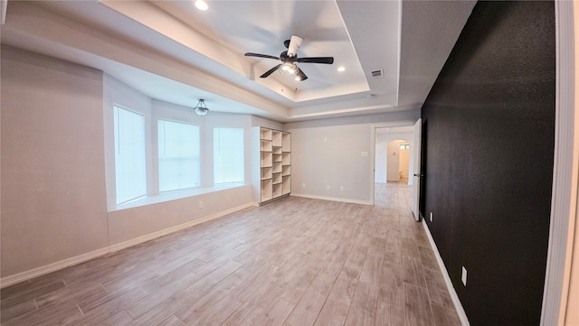 interior space featuring a raised ceiling, baseboards, visible vents, and light wood-style flooring