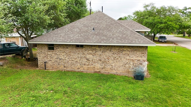 view of side of home featuring a yard, a shingled roof, and brick siding