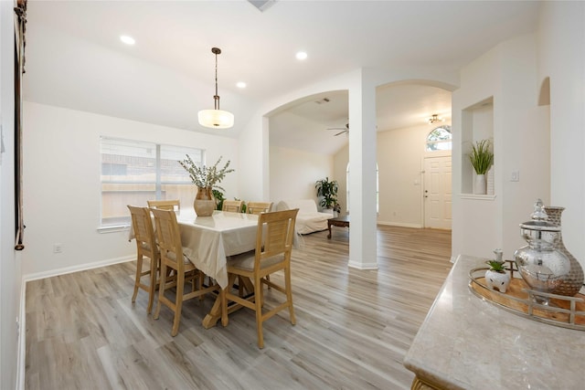 dining area with arched walkways, plenty of natural light, and light wood-type flooring