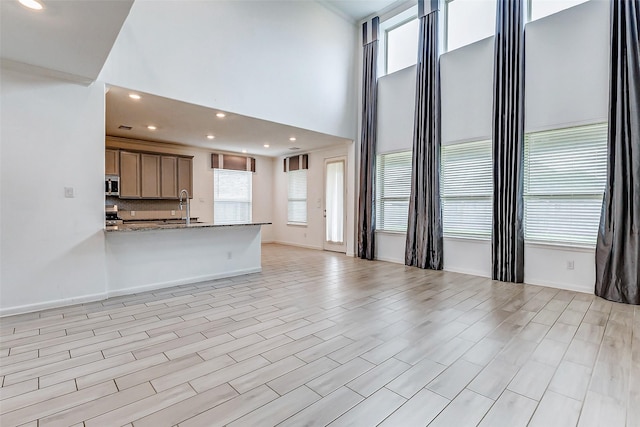 3007 Velda May Dr, Richmond, TX 77406 - unfurnished living room with a sink, a high ceiling, and a healthy amount of sunlight
