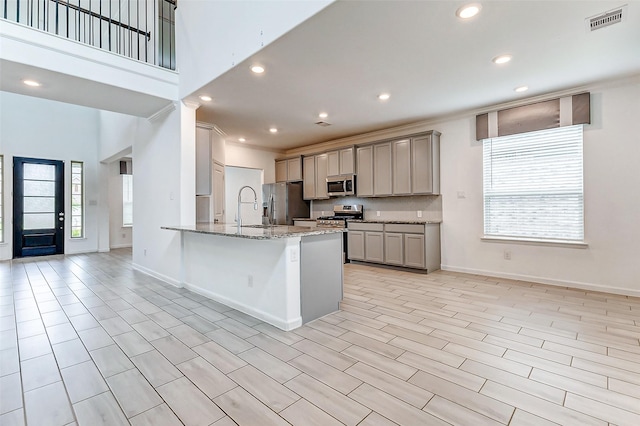 3007 Velda May Dr, Richmond, TX 77406 - kitchen featuring gray cabinets, a wealth of natural light, appliances with stainless steel finishes, and light stone countertops