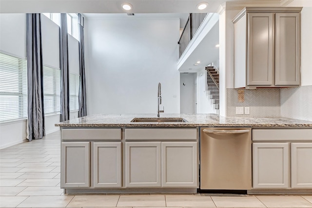3007 Velda May Dr, Richmond, TX 77406 - kitchen with light stone counters, a peninsula, decorative backsplash, stainless steel dishwasher, and a sink