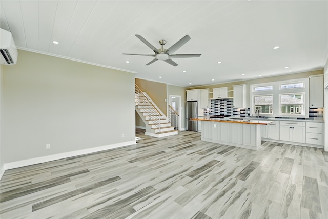 4102 Kiva Rd, Galveston, TX 77554 - kitchen featuring tasteful backsplash, a wall mounted air conditioner, white cabinetry, freestanding refrigerator, and butcher block counters