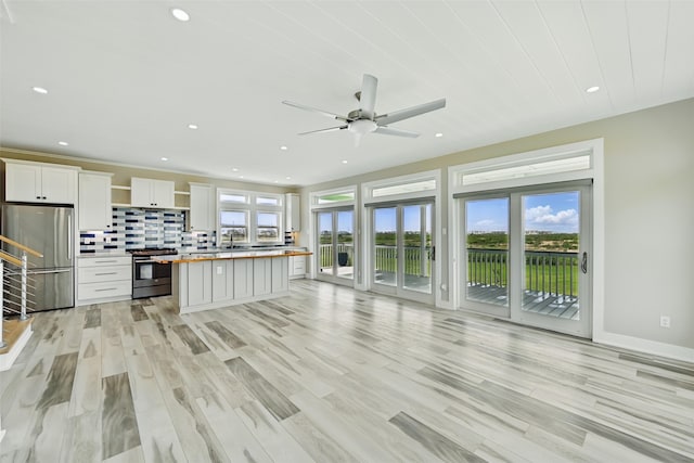 4102 Kiva Rd, Galveston, TX 77554 - kitchen featuring a ceiling fan, light wood-style floors, white cabinetry, stainless steel appliances, and backsplash