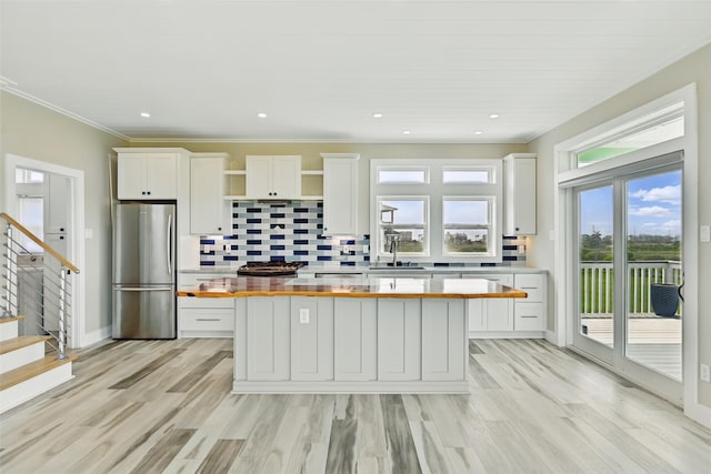 4102 Kiva Rd, Galveston, TX 77554 - kitchen with a sink, wooden counters, freestanding refrigerator, white cabinetry, and a kitchen island