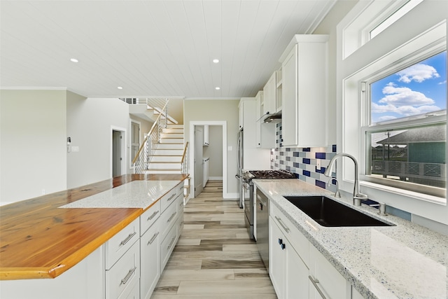 4102 Kiva Rd, Galveston, TX 77554 - kitchen featuring butcher block countertops, backsplash, white cabinets, wood ceiling, and a sink