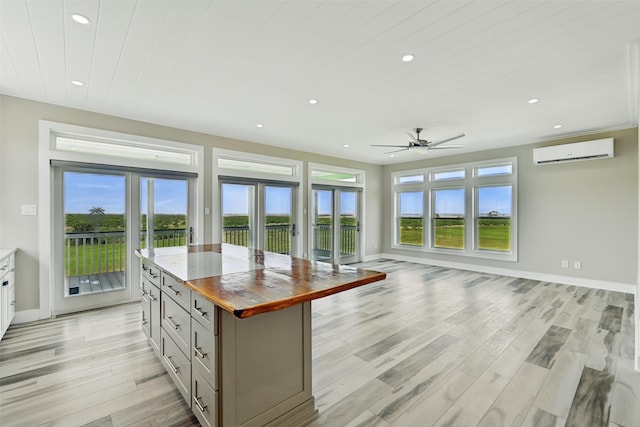 4102 Kiva Rd, Galveston, TX 77554 - kitchen featuring butcher block countertops, a healthy amount of sunlight, ceiling fan, and a wall unit AC