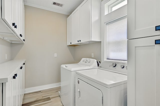 4102 Kiva Rd, Galveston, TX 77554 - washroom with baseboards, washing machine and dryer, light wood-style floors, visible vents, and cabinet space