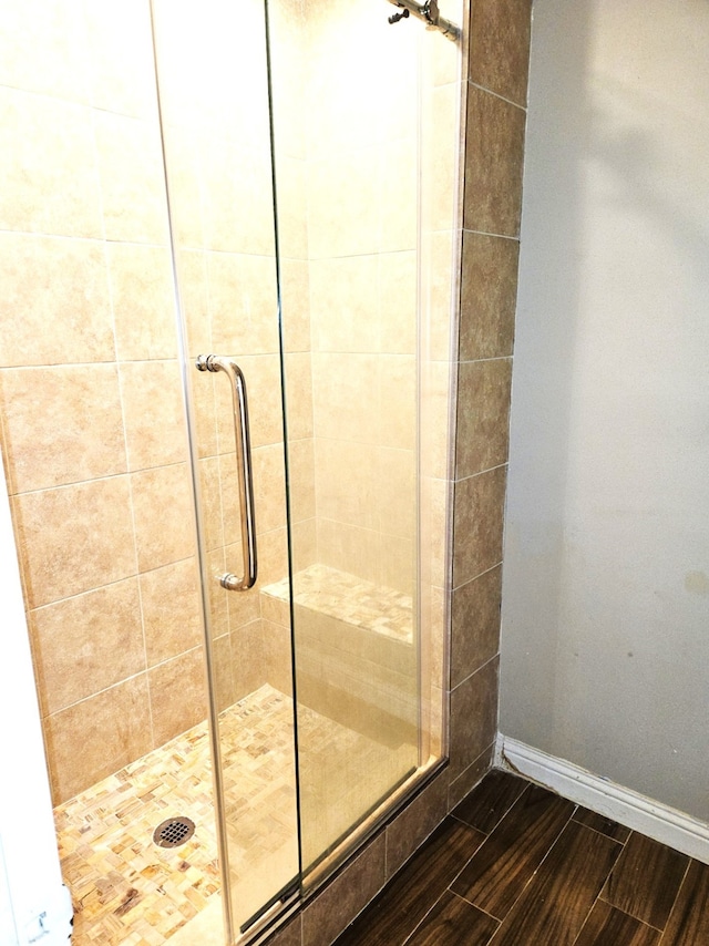 bathroom with a stall shower, wood finished floors, and baseboards
