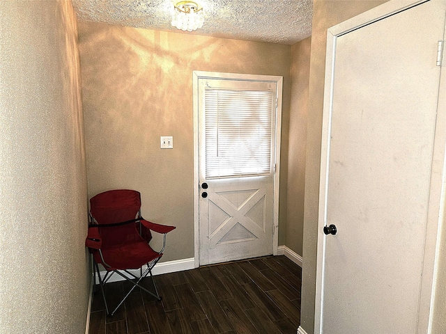 doorway to outside with baseboards, a textured ceiling, and dark wood finished floors