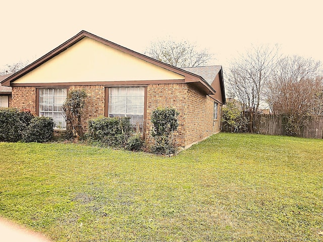 view of home's exterior with a yard, fence, and brick siding