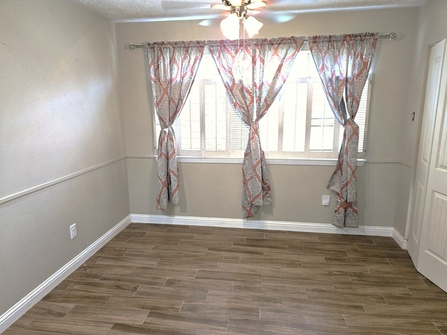 unfurnished dining area featuring baseboards, a ceiling fan, and wood finished floors