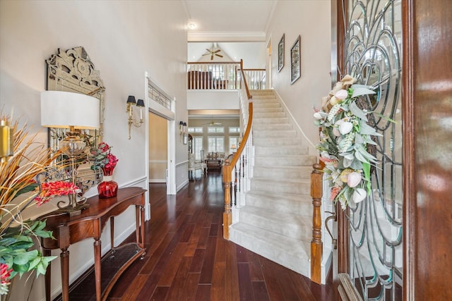 entrance foyer featuring baseboards, a ceiling fan, a towering ceiling, wood finished floors, and stairs