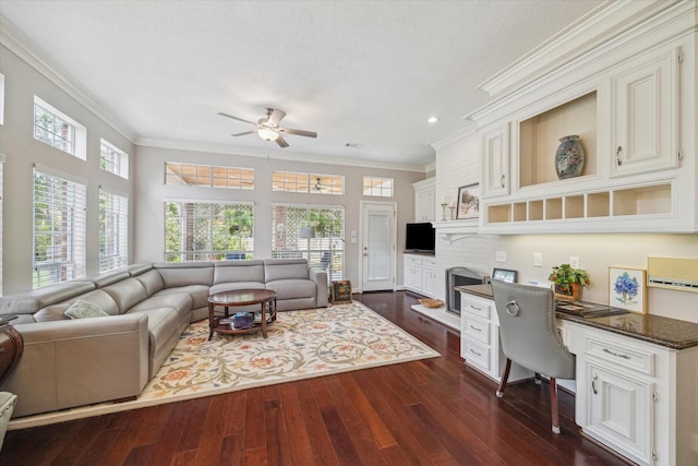 living room featuring dark wood finished floors, ornamental molding, built in study area, and a ceiling fan