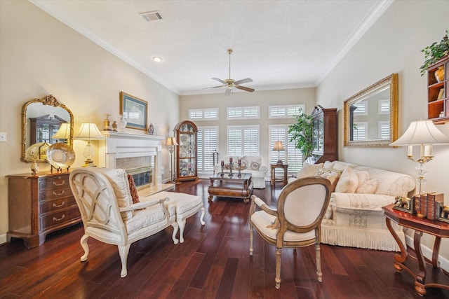 living room featuring a tiled fireplace, ceiling fan, wood finished floors, and crown molding