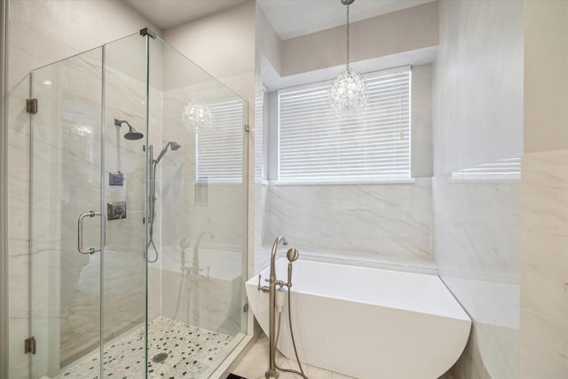 full bathroom featuring a marble finish shower, an inviting chandelier, and a soaking tub