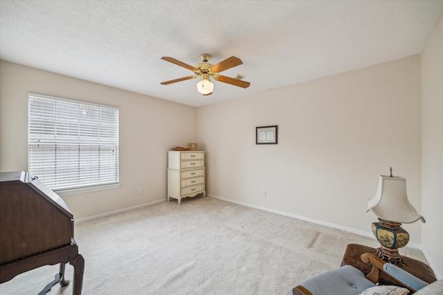 bedroom featuring ceiling fan, a textured ceiling, light colored carpet, and baseboards