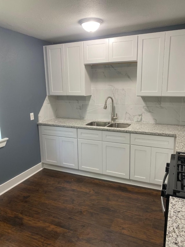 kitchen with a sink, range with gas stovetop, white cabinetry, and dark wood-type flooring