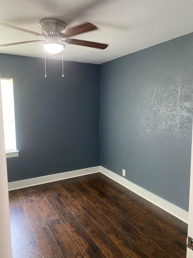 spare room featuring ceiling fan, a textured ceiling, baseboards, and dark wood-style floors