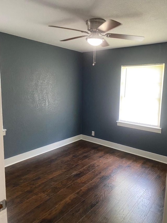 empty room with dark wood-style flooring, baseboards, and a ceiling fan