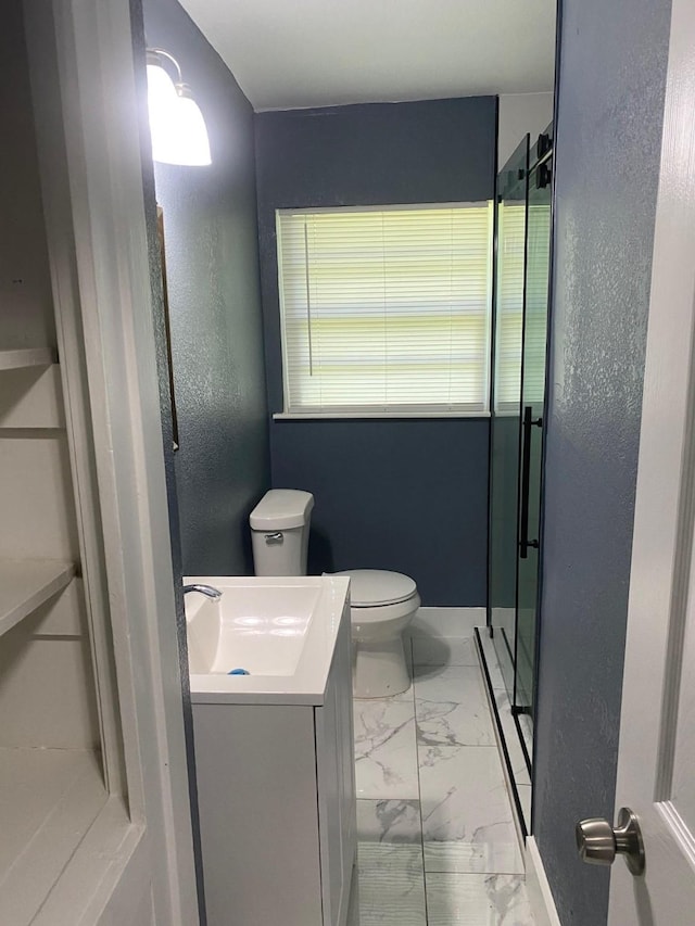 full bathroom featuring vanity, toilet, marble finish floor, a stall shower, and a textured wall