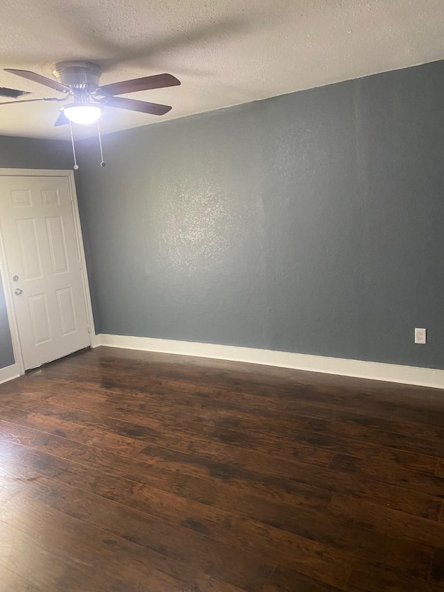 unfurnished bedroom with dark wood-type flooring, a textured ceiling, baseboards, and ceiling fan