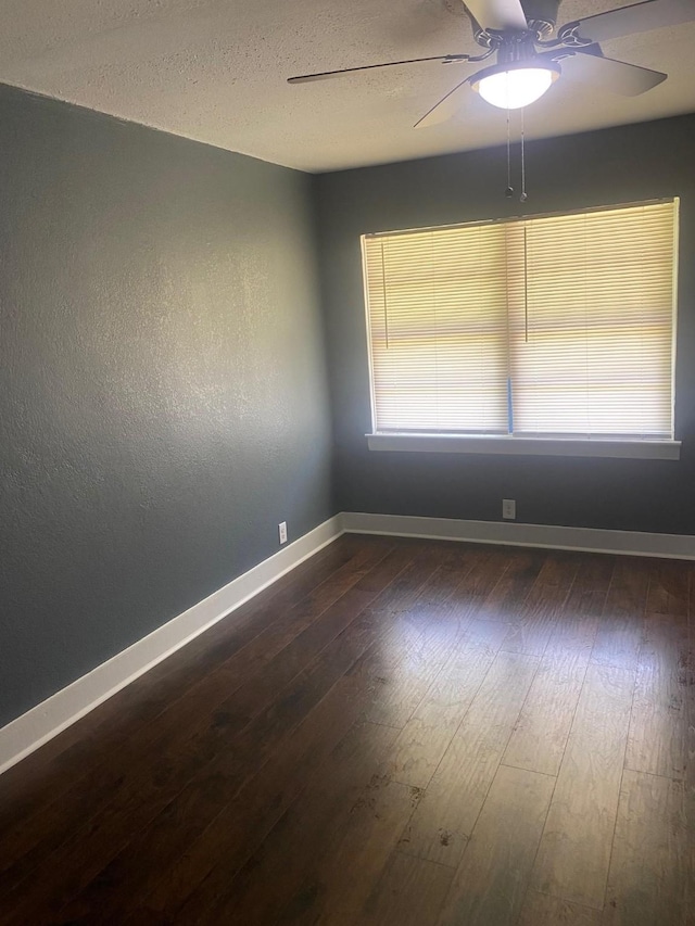 unfurnished room featuring dark wood-style flooring, baseboards, and a ceiling fan