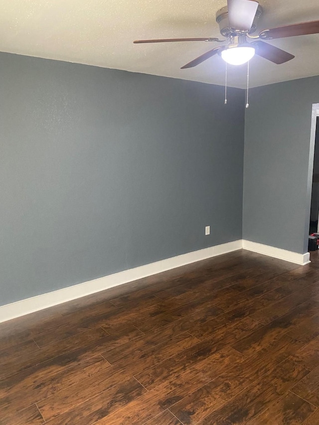 spare room with baseboards, a ceiling fan, and dark wood finished floors